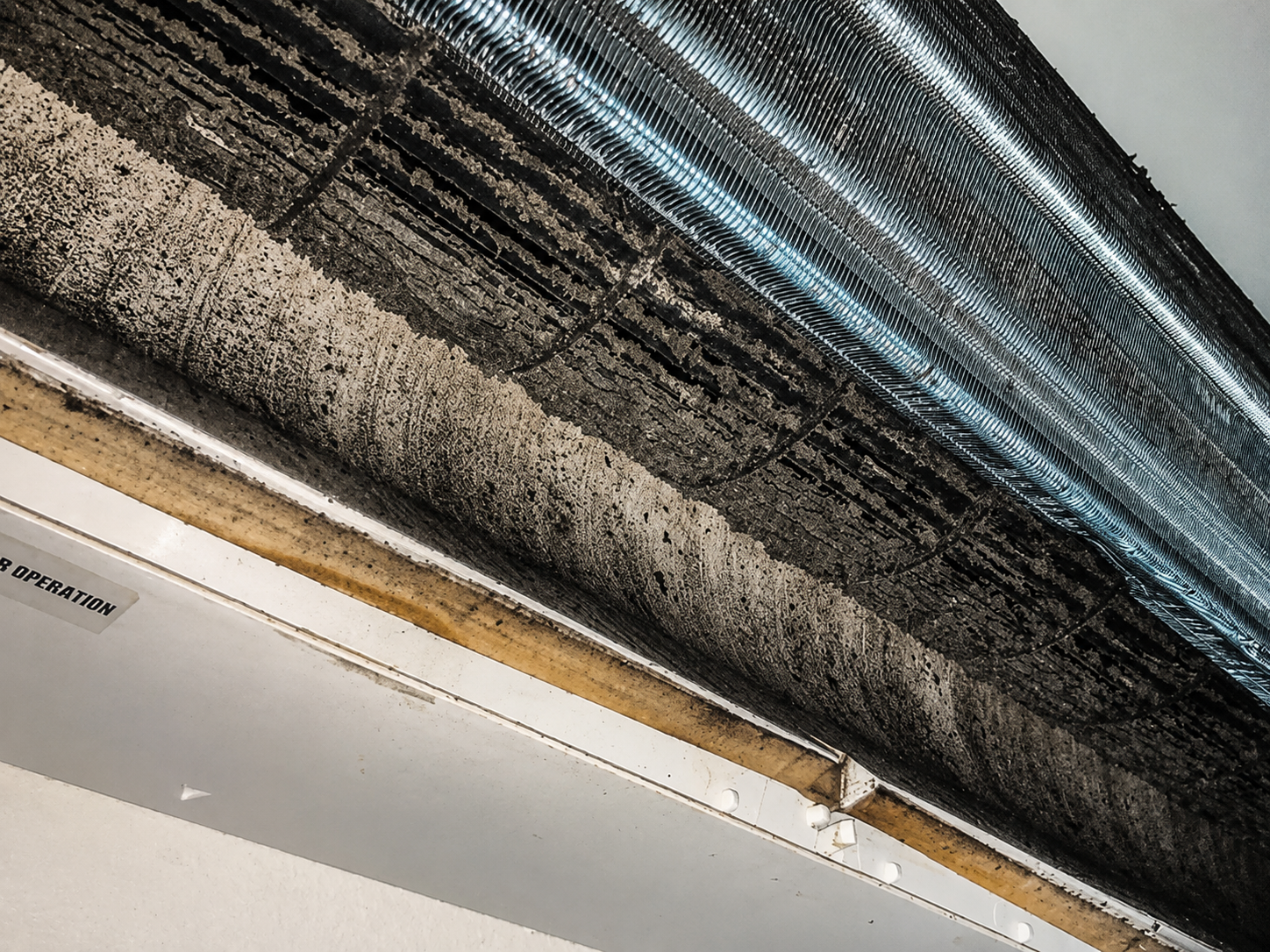 A filthy indoor air conditioner evaporator coil caked in dust and grime before a chemical clean